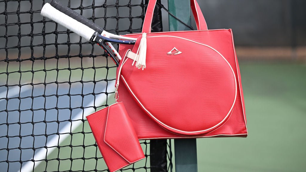 Red tennis bag with a racket on a tennis court