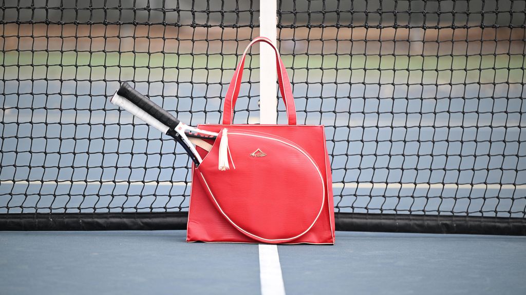 Red bag with a tennis racket on a tennis court