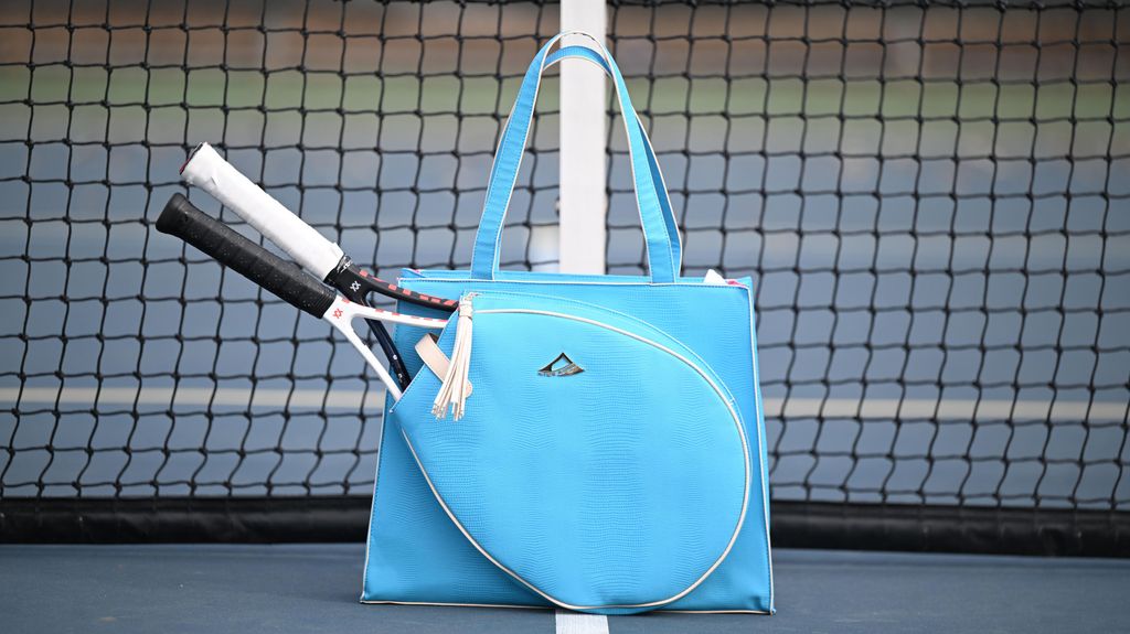 Blue tennis bag with rackets on a tennis court
