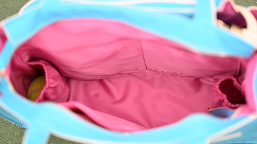 Close-up of a pink garment inside a blue tennis bag with a yellow object.