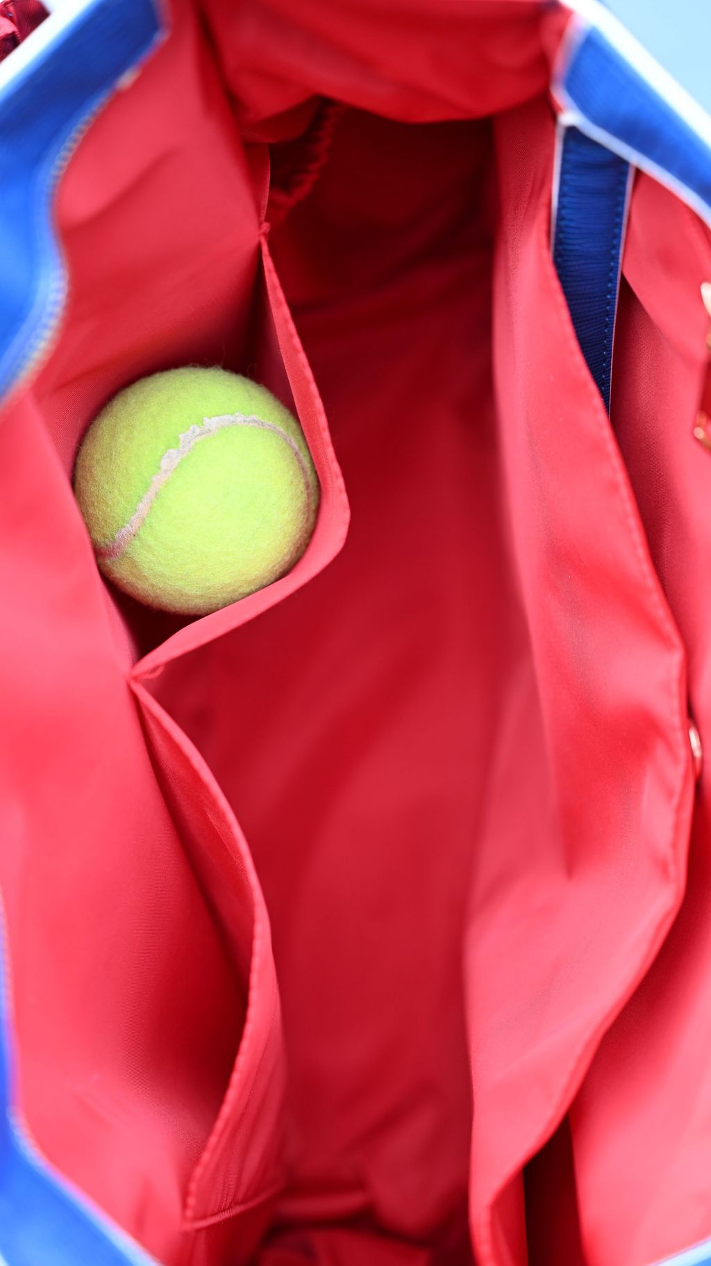 Tennis ball inside a red bag with blue accents